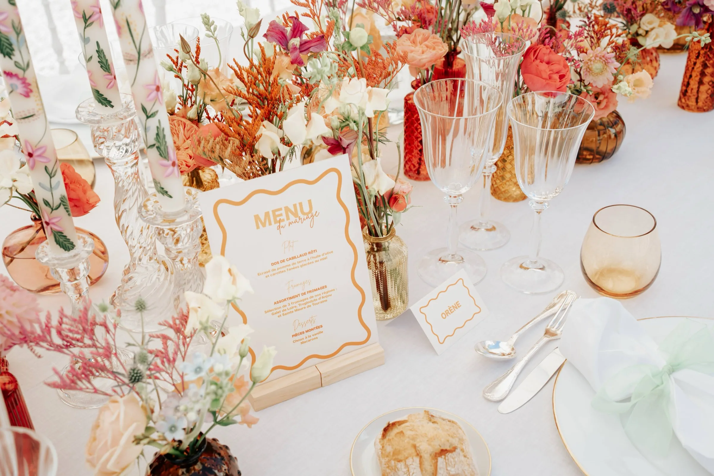 Table de réception dressée : menu, fleurs aux tons orangés et verres ambrés