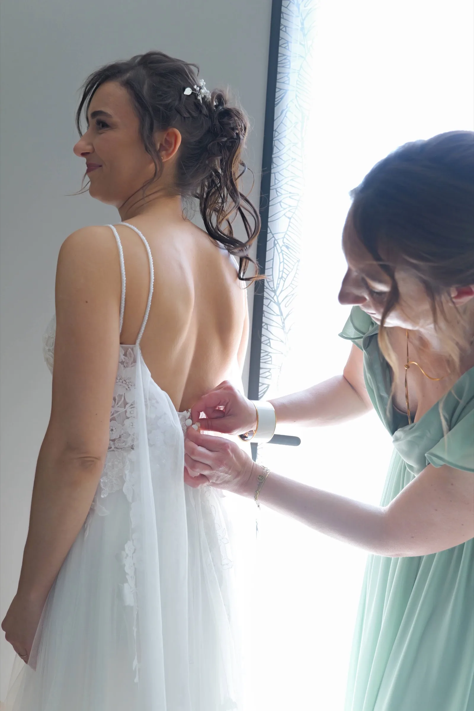 Une demoiselle d’honneur ferme la robe de la mariée