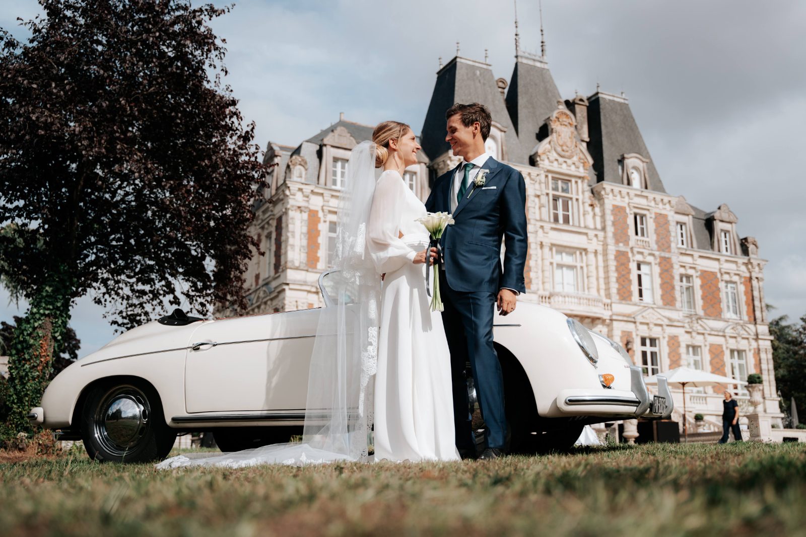 Les mariés devant une voiture ancienne, un château en arrière-plan