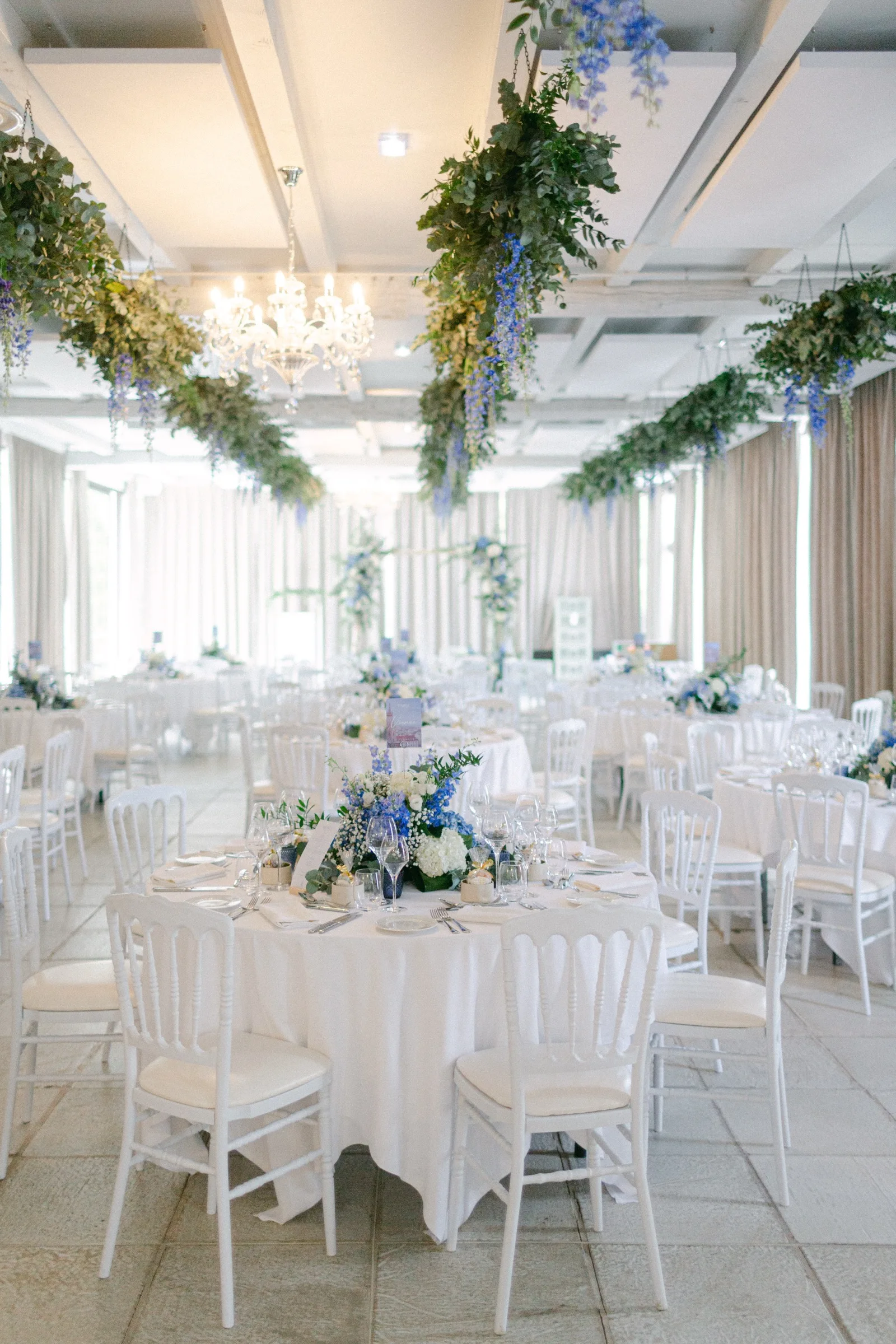 Salle de réception dressée de tables rondes et de fleurs bleu pastel